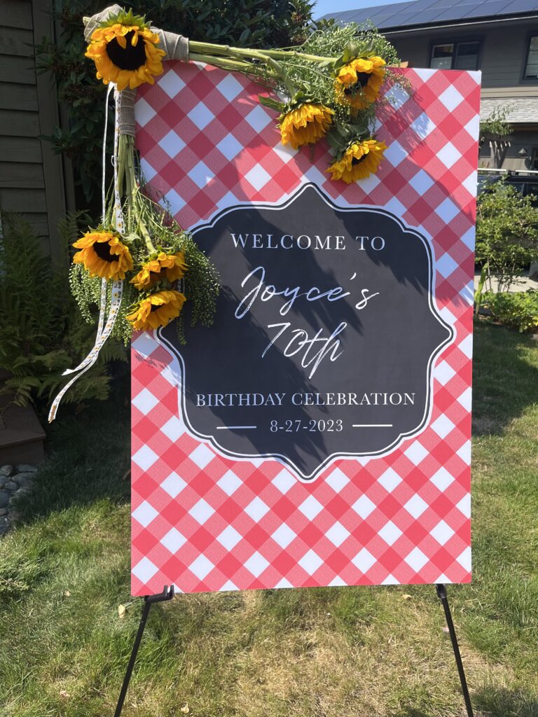 Welcome sign for a 70th birthday celebration framed with sunflowers